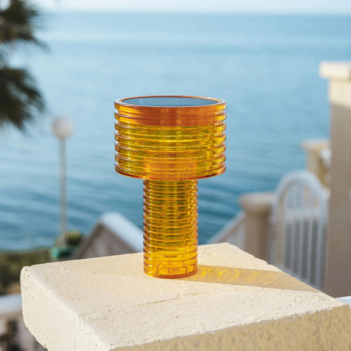 Compact solar table lamp with warm LED light, USB-C charging, and up to 20 hours of autonomy for indoor and outdoor use.