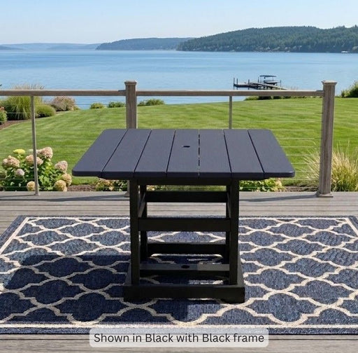 Krahn Dining Table in black on a deck with a view of the water in the background