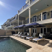 Frankford Greenwich 7.5' Square Umbrella in Captian Navy colour with lounges by a pool