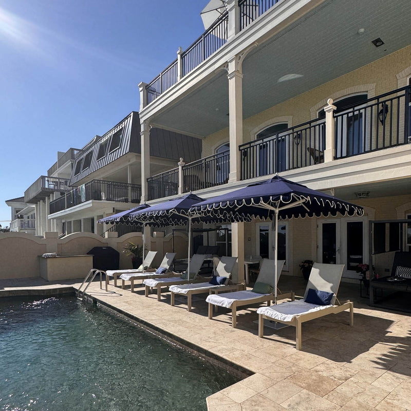 Frankford Greenwich 7.5' Square Umbrella in Captian Navy colour with lounges by a pool