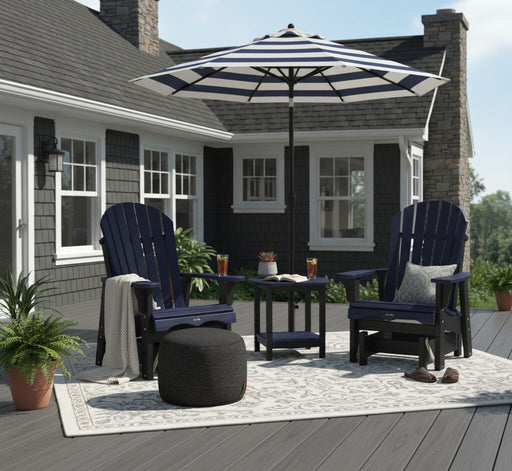 Outdoor patio setup with two blue Krahn Adirondack Gliders, a striped Basil Bangs umbrella, a Fatboy ottoman, and a Krahn End table on a deck.