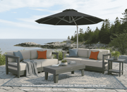 Krahn Outdoor Deep Seat patio set with loveseat sectional sofa, 44" rectangular coffee table, and Frankford Aurora cantilever umbrella on a patio with ocean view.