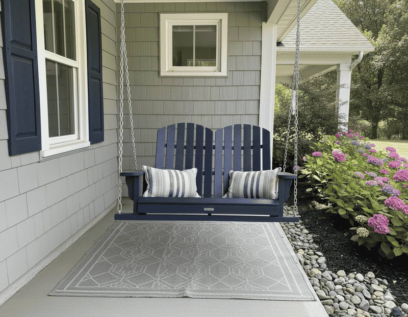 Krahn Porch Swing in Navy hanging from chains under a veranda