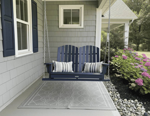 Krahn Porch Swing in Navy hanging from chains under a veranda