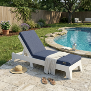 White chaise lounge chair with blue cushions by a poolside in a garden setting